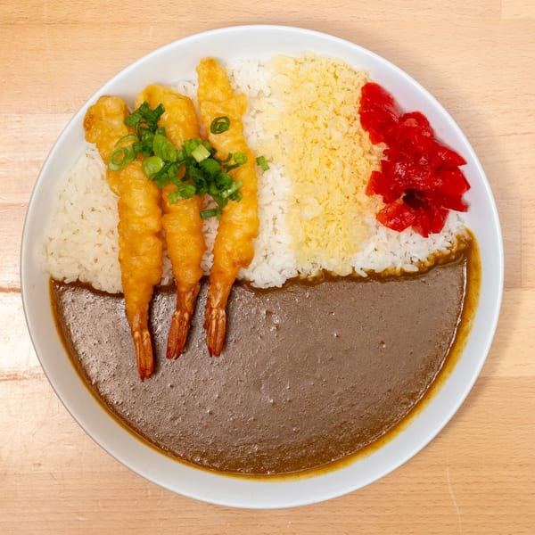 Japanese curry with three fried shrimp, white rice, tempura flakes, and red pickled ginger.