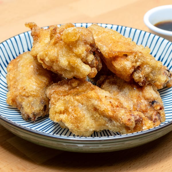 Crispy Japanese fried chicken karaage pieces on a blue and white striped plate with a dipping sauce.