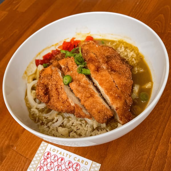 Curry Do's Japanese curry udon with sliced fried chicken katsu, red peppers, and green onions.