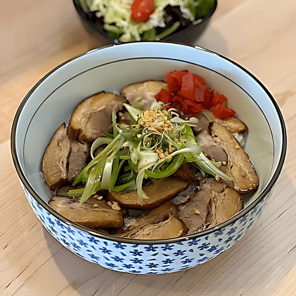 Japanese chashu pork bowl with green onions, pickled ginger, and peanuts in a patterned bowl.
