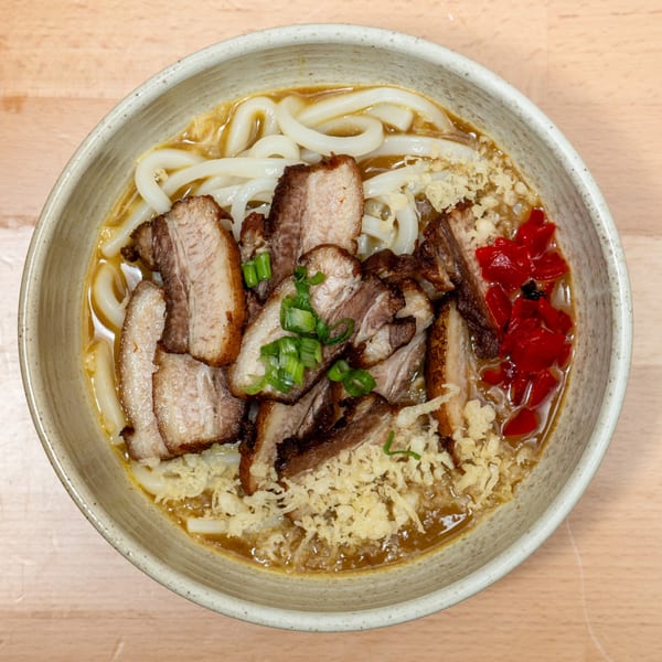 Curry Do's Japanese udon noodle soup with sliced pork belly, green onions, and red pickled ginger.