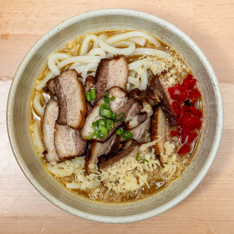 Curry Do's Japanese udon noodle soup with sliced pork belly, green onions, and red pickled ginger.