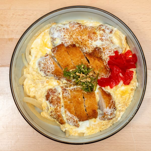 A Japanese katsudon bowl with crispy fried pork cutlets, egg, onions, and red pickled ginger.