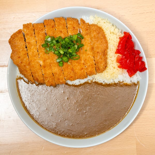 Japanese Curry Do dish with sliced tonkatsu, rice, curry sauce, green onions, and red pickled ginger.