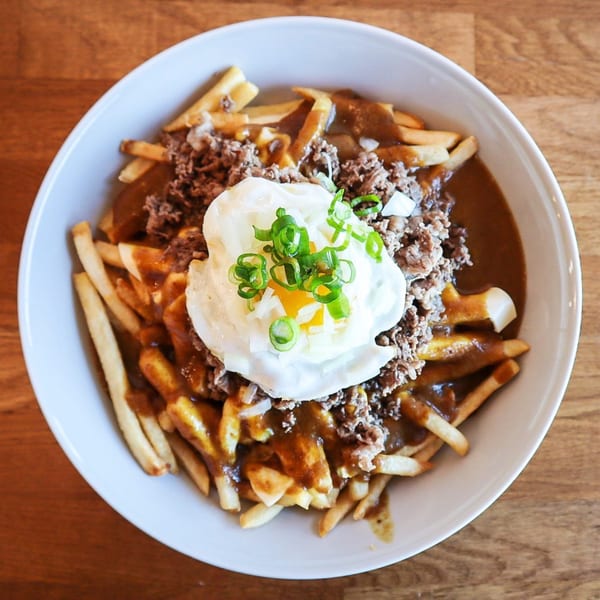 Curry Do's Japanese poutine with fries, gravy, ground meat, a fried egg, and green onions.