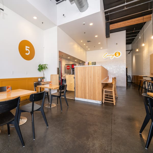 Interior of Curry Do, a Japanese restaurant, with tables, chairs, and a service counter.